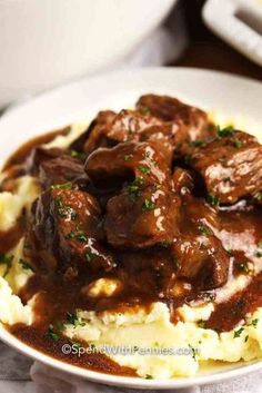 a white plate topped with mashed potatoes and beef