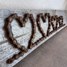 the word love is made out of chains on a white wooden plank with a heart