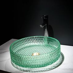 a green glass bowl sink sitting on top of a counter next to a faucet