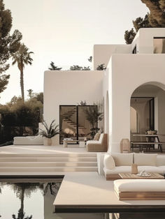 an outdoor living area with couches and tables next to a pool in front of a house