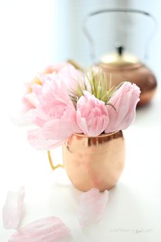 pink flowers in a copper mug on a white table