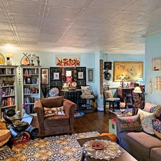 a living room filled with lots of furniture and bookshelves covered in pictures on the walls