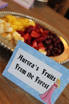 there is a plate of fruit on the table with a name tag in front of it that says, aurora's fruits from the forest