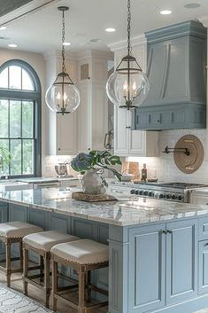 a large kitchen with blue cabinets and marble counter tops, two stools at the island