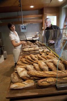 a woman standing in front of a counter filled with bread