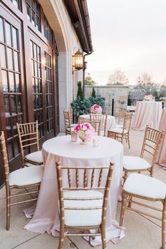 tables and chairs are set up outside for an outdoor wedding reception with pink flowers in vases