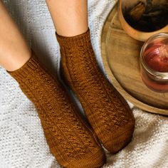 a woman's legs with brown socks and a jar of fruit on a table