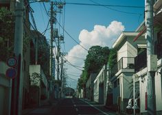 an empty street with power lines above it and buildings on both sides, in the daytime