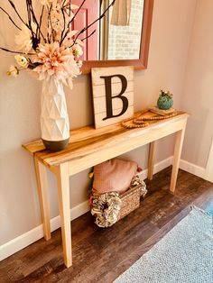 a vase with flowers on top of a wooden table next to a sign that says b