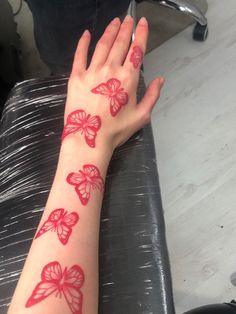 a woman's arm with red butterflies on it and her hand resting on the table