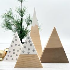 three wooden christmas trees sitting on top of a white table next to a pine tree