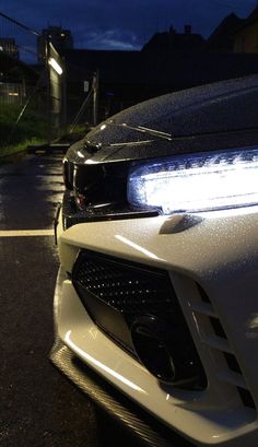 the front end of a white sports car at night