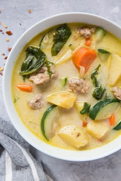 a white bowl filled with meat and veggies next to a napkin on top of a table