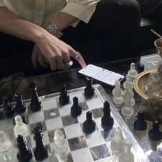 a man is playing chess on a glass table