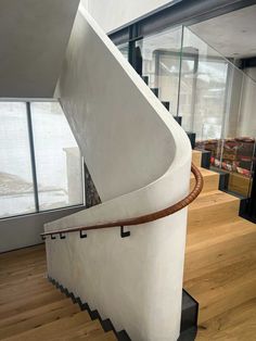 a spiral staircase with wooden handrails in a modern house, leading up to the second floor