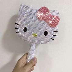 a hand holding a hello kitty mask with sequins