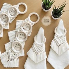 several white napkins with tassels and plants on the table next to them