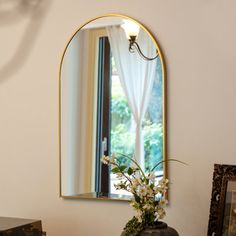 a vase with flowers is sitting on a table in front of a mirror and other items