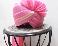 a pink turban sitting on top of a metal table next to a white wall