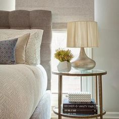 a bed room with a neatly made bed and a lamp on the side table next to it