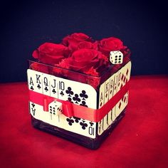 a card box with roses in it sitting on a red tableclothed surface next to a black wall