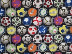 many soccer balls are lined up on a wire rack and one is painted with different colors