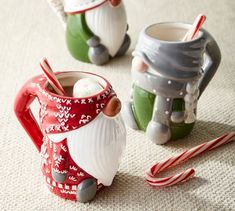 two santa mugs with candy canes on the floor next to one and another