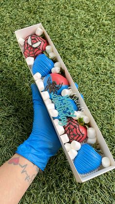 a person in blue gloves holding a box with fake spiderman decorations on it's sides