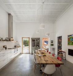 an open kitchen and dining room with white walls, flooring and ceiling lighting is shown