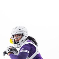 a female lacrosse player in purple and white uniform holding a yellow ball with her right hand