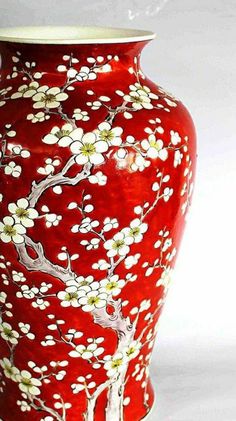 a red vase with white flowers painted on it