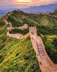 the great wall of china at sunset with people walking on it and mountains in the background