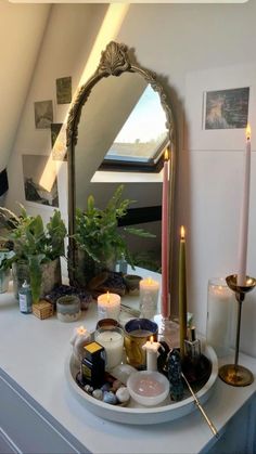 candles and other items on a table in front of a mirror with an arched frame