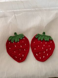 two crocheted strawberries sitting on top of a white sheet