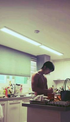 a shirtless man is preparing food in the kitchen