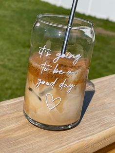 a glass with some liquid in it sitting on a wooden table next to the grass