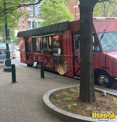 a red food truck parked next to a tree