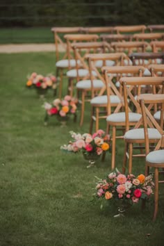 rows of wooden chairs with flower arrangements on the back are lined up for an outdoor ceremony