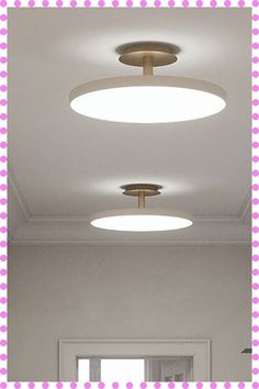 three circular lights are hanging from the ceiling in a room with pink polka doted walls