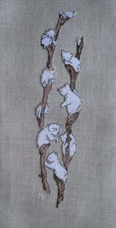 an embroidered piece of cloth with flowers and leaves on the side, in white and brown colors