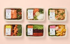 four trays with different types of food in them on a light pink background, top view