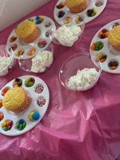 some cupcakes are on plates with white frosting and candy candies around them