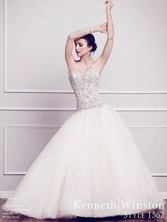 a woman in a wedding dress is posing for the camera with her arms up and hands behind her head