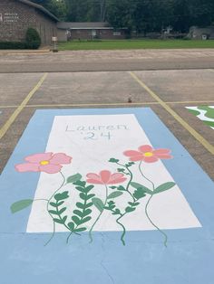 a parking lot with flowers painted on the ground in front of it and an inscription that reads lauren 2 / 4