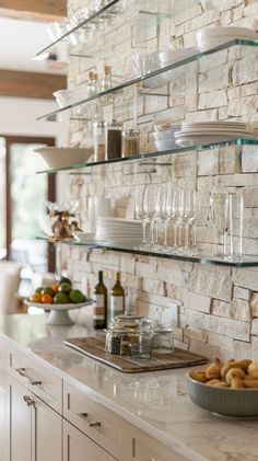 a kitchen counter with wine glasses, plates and bowls sitting on it's shelves