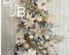 a white christmas tree with gold and silver ornaments on it's top, in front of a wooden wall