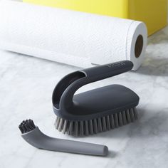 a close up of a brush on a counter near a roll of toilet paper