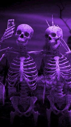 two skeletons sitting next to each other in front of a purple background with the cell phone