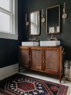 a bathroom with two sinks, mirrors and rugs on the floor in front of it