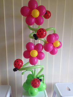 a vase filled with balloons and flowers on top of a table